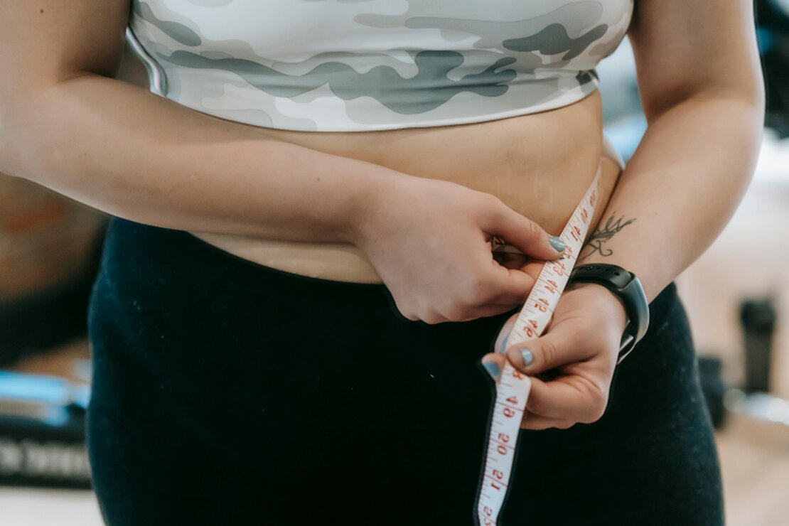 Client measuring waist as part of a slimming support programme
