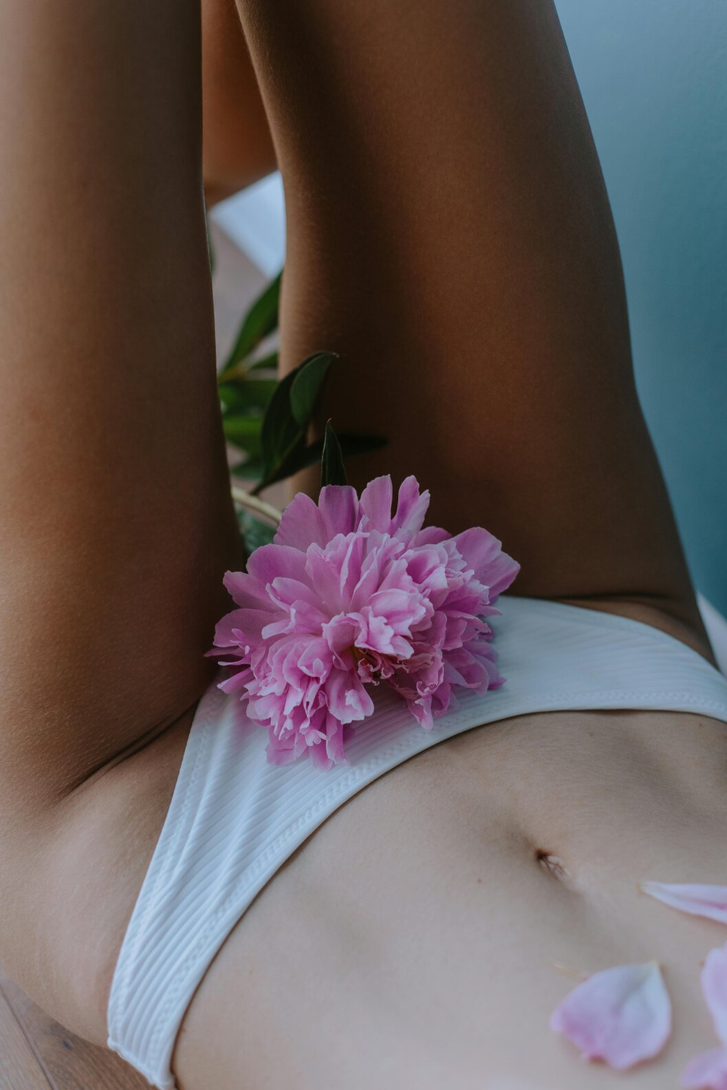Close-up of a woman’s lower body covered with a towel during a Brazilian wax treatment